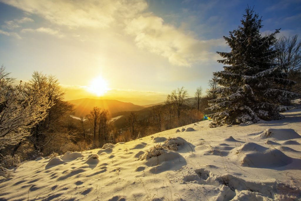 Sun rising above hills covered with snow in winter nature