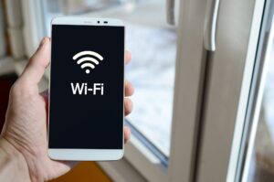 A person sees a white inscription on a black smartphone display that holds in his hand. Wi-Fi